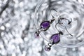 Beautiful pair of silver earrings with amethyst gemstones on blurred background