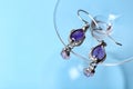 Beautiful pair of silver earrings with amethyst gemstones on blue background