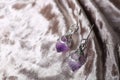 Beautiful pair of silver earrings with amethyst gemstones on light fabric