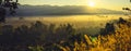 panorama landscape of the sunrise, The sun's rays through at the top of the hill and the moving fog over the tree i Royalty Free Stock Photo