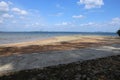 Beautiful panorama landscape view of an empty yellow sand beach in shadow, turquoise ocean water, light blue sky, white clouds and Royalty Free Stock Photo