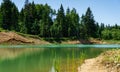 Beautiful panorama of quarry lake with emerald green water and big forest as background Royalty Free Stock Photo