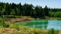 Beautiful panorama of quarry lake with emerald green water and big forest as background Royalty Free Stock Photo