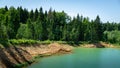 Beautiful panorama of quarry lake with emerald green water and big forest as background. Closed down quarry now