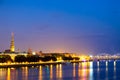 Beautiful panorama of Riga center over Daugava river with St Peters Church and railroad bridge during amazing sunset. View of illu Royalty Free Stock Photo