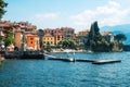 Panorama of colorful lakefront villas in Varenna, Italy, with boats moored at the shore.