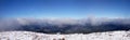 A beautiful panorama view of the snow-capped mountains of the Carpathians from the top of Goverly in spring in a beautiful sunny