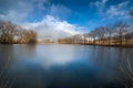 panoramic landscape on a pond and the reflection of reeds, sky and trees in the water of early spring Royalty Free Stock Photo