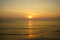 Beautiful panoramic morning sunrise seaview with wave water reflection through sand beach, shades of soft wide orange color sky Royalty Free Stock Photo