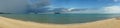 Beautiful panoramic sea view and clean beach wth three island and rainy cloud coming from left side of picture, colouful blue