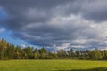 Beautiful panoramic view of autumn landscape with forest colorful trees and green field on background of blue sky with clouds. Royalty Free Stock Photo