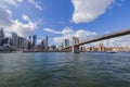 Beautiful panoramic view of Brooklyn Bridge over Hudson River and skyscrapers of Manhattan on against blue sky with white clouds. Royalty Free Stock Photo