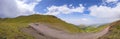Beautiful panoramic view of green mountains with dangerous gravel road. Ketmen or Ketpen mountains gorge and mountain pass.