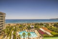 Beautiful panoramic view of hotel area with outdoor pool and green trees and plants on endless blue sea water surface.