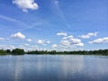 Beautiful panoramic view of a lake in front of a forest under the blue sky with clear clouds Royalty Free Stock Photo
