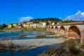 Colorful and joyful scene of spring in Tuscany, old stone bridge over river, yellow and white buildings on the hill Royalty Free Stock Photo