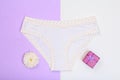 Beautiful panties with gift box and flower bud on lilac and white background. Women underwear set. Romantic lingerie.