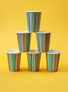 Beautiful paper cups stacked in a pyramid. Bright yellow background. Minimalism