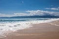 Beautiful paradise sandy beach, sea waves, foam, blue sky, white clouds. Royalty Free Stock Photo