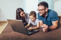 Parents and their son are doing shopping online using laptop and smiling at home Royalty Free Stock Photo