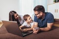 Parents and their son are doing shopping online using laptop and smiling at home Royalty Free Stock Photo