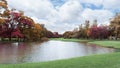 Beautiful park in an autumn season, yellow and orange colorful  leaves of the trees on green grass fresh lawn near a lake, under Royalty Free Stock Photo