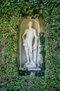 Beautiful park hedge with white ancient roman statue of man. Lush Green Topiary