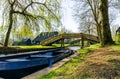 A beautiful park with a parked boat and a bridge over a water canal in a historical Dutch village De Kruumte. Royalty Free Stock Photo