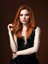 Beautiful passion look young woman with volume red hair style on orange dark orange color studio background. Closeup