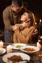Beautiful passionate couple having a romantic candlelight dinner celebrating Valentines Day at home, kissing Royalty Free Stock Photo