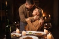 Beautiful passionate couple having a romantic candlelight dinner celebrating Valentines Day at home, kissing. Royalty Free Stock Photo