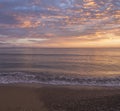 Beautiful pastel pink orange and golden sunset clouds and waves at sea shore Agios Georgios Pagon beach at Corfu island, Greece Royalty Free Stock Photo