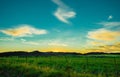 Beautiful pasture field below the mountain against a cloudy sunset sky