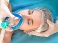 Beautiful patient receives anaesthetic. Close up face of a patient and hands of a doctor. Royalty Free Stock Photo