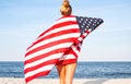 Beautiful patriotic woman with American flag on the beach. USA Independence day, 4th July. Freedom concept