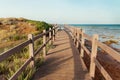 Beautiful peaceful landscape with wooden pier, grass covered hill, calm sea and blue sky Royalty Free Stock Photo