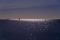 Beautiful peaceful seascape with small ship and lighthouse silhouette on the sea horizon Royalty Free Stock Photo