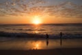 Beautiful and peacful sunset over ocean and beach with silhouette of 2 children playing