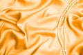 Beautiful pearls on light orange silk, top view