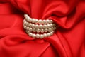 Beautiful pearls with red silk as background, closeup Royalty Free Stock Photo