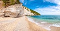 Beautiful pebble beach surrounded by high massive white limestone rocky cliffs eroded by Adriatic sea waves and wind. Green Aleppo Royalty Free Stock Photo