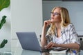 beautiful pensive blonde woman using laptop while working