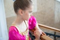 Beautiful pensive small girl in traditional purple dress standing indoors leaning on wooden railing