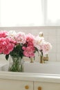 Beautiful peonies in vase in sink on background of brass faucet and window in new scandinavian house. Pink peony flowers in modern Royalty Free Stock Photo