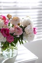 Beautiful peonies in vase on table near window Royalty Free Stock Photo