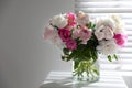 Beautiful peonies in vase on table near window. Space for text Royalty Free Stock Photo