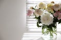 Beautiful peonies in vase on table near window. Space for text Royalty Free Stock Photo