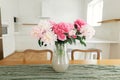 Beautiful peonies in vase on wooden table on background of stylish white kitchen with appliances in new scandinavian house. Modern Royalty Free Stock Photo