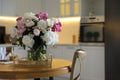 Beautiful peonies in vase on table in kitchen. Space for text Royalty Free Stock Photo