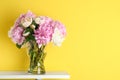 Peonies on white table against yellow background. Space for text Royalty Free Stock Photo